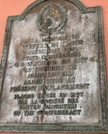 A weather-stained plaque reading: "À la mémoire de Jefferson Davis président des États confédérés qui séjourna en 1867 au domicile de John Lovell alors situé au présent emplacement
Plaque érigée en 1957 par la société des United Daughters of the Confederacy"