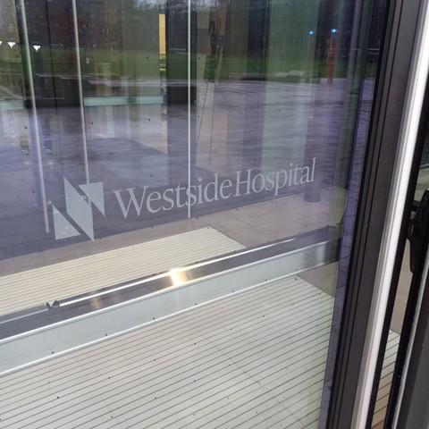 A glass door with a white logo and lettering ("Westside Hospital").