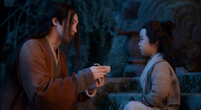 Wen Ning holding a bowl of soup in his hands and he is about to feed some to Wen Yuan sitting in front of him