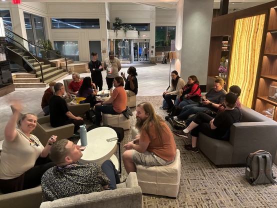 A view of 16 Python people spread out across multiple tables, chairs, and sofas in the lobby of the Westin hotel.