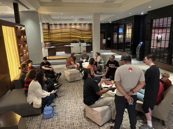 A view of 16 Python people spread out across multiple tables, chairs, and sofas in the lobby of the Westin hotel.