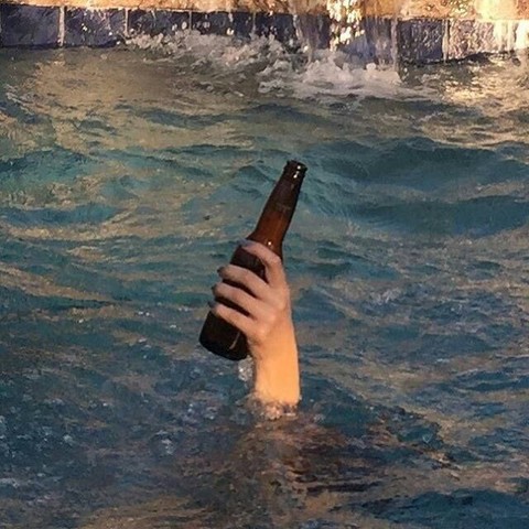 hand holding a beer bottle out of the water