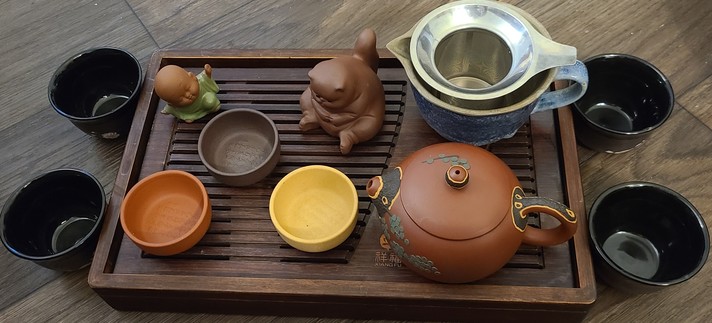 Zisha clay tea set on gongfu tray with additional cups. Chubby cat and small budai teapets accompany me.