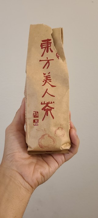 Natural-colored paper pouch with red calligraphy held up on a white background