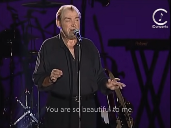 Joe Cocker singing at a concert with the subtitles 