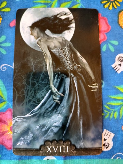 Card from the Tarot V deck. 
The Moon-XVIII.
A female vampire, wearing blue long skirt and a corset top, her back to the viewer, but we can partially see the left side of her and her face. She is angrily hollering. A full moon in the night sky. 