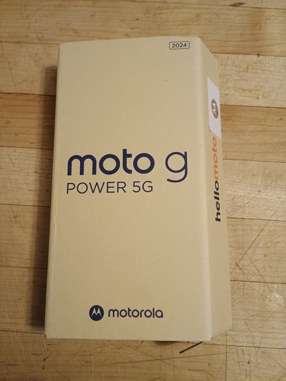 A photo of a rectangular tan box sitting on a butcher block counter.  The logotype for a Motorola Moto G Power 5G is centered in a rounded, modern font.