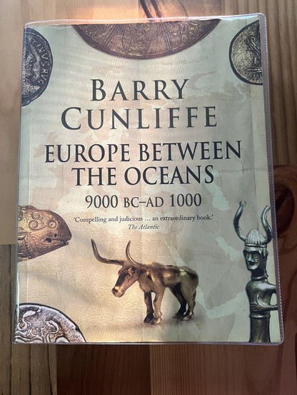 A physical copy of “Europe Between the Oceans” by Barry Cunliffe on a wooden desk