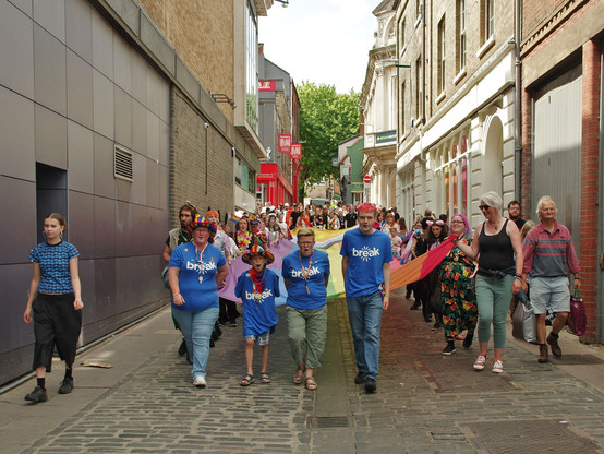 Break charity marchers on the front of a 50' rainbow flag being caried down the cobbled street