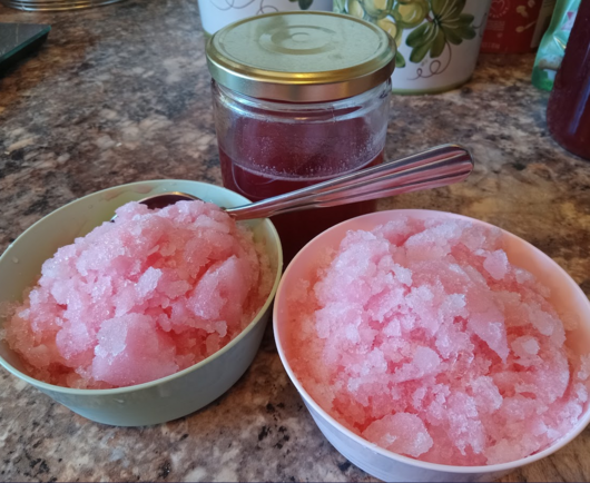 photo of two bowls of snow cones that are slightly pink from the addition of rhubarb syrup, a jar of said syrup is visible behind them