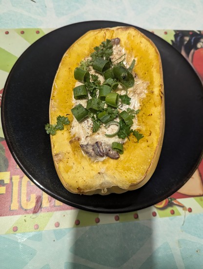 Moitié de courge spaghetti fourrée à la crème avec de la ciboule et du persil pour décorer 