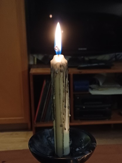 White candle with streams of solidified black candle wax on the sides