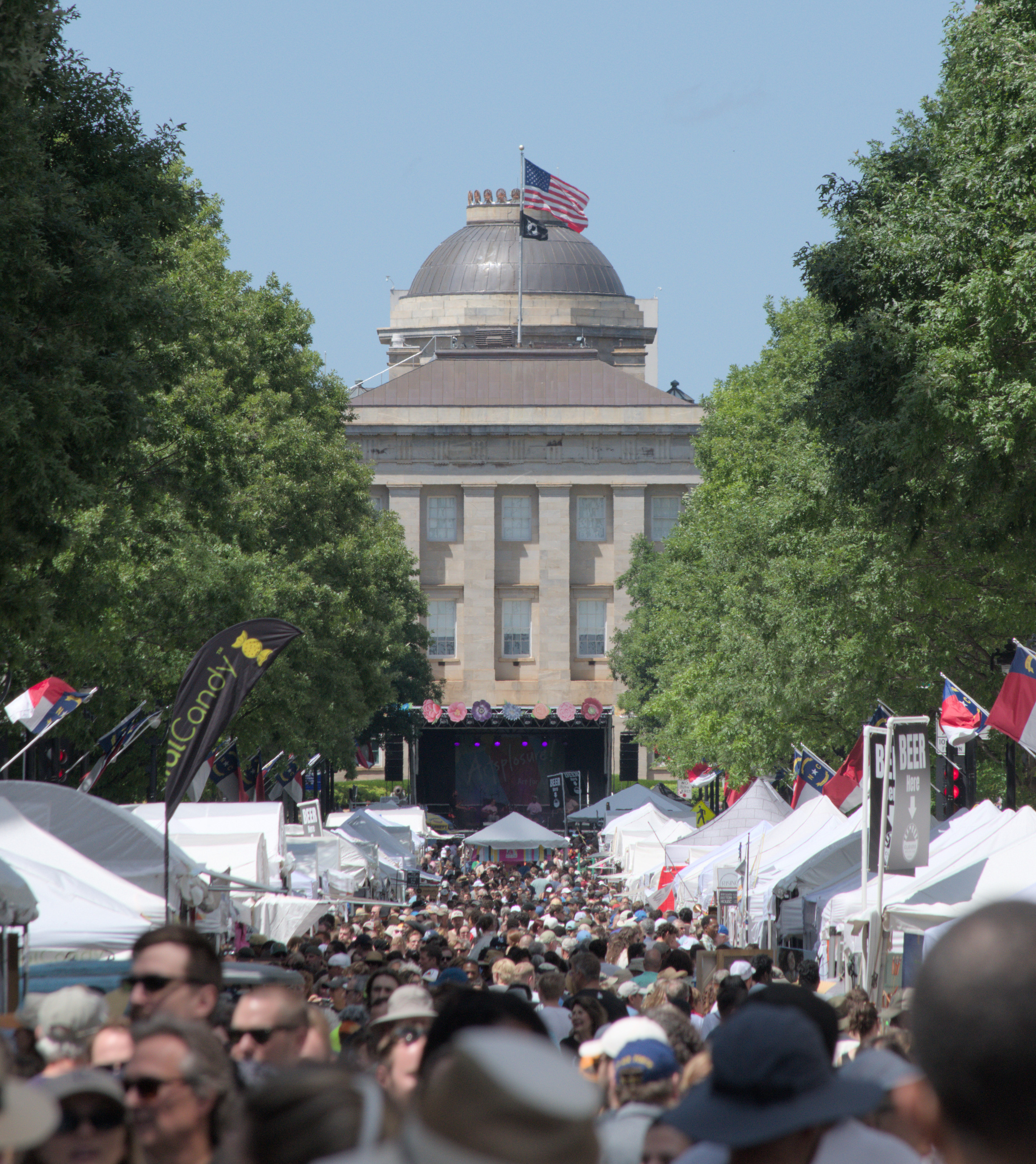 A close up view of the state capitol building, still showing the packed street leading up to it. It's a bright sunny day with blue sky and green trees line the street.