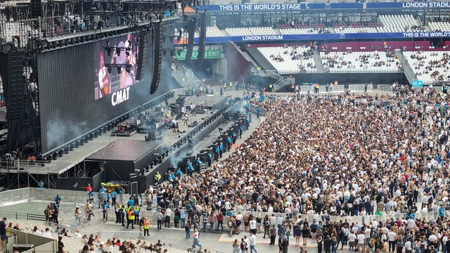 A massive crowd at a stadium gig, from up in the stands. Not everyone is here yet. CMAT is on stage.