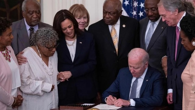 Opal Lee stands with Vice President Kamala Harris, and watches as President Joe Biden signs a bill into law establishing the Juneteenth national holiday on June 17, 2021. She had worked many decades for this.
