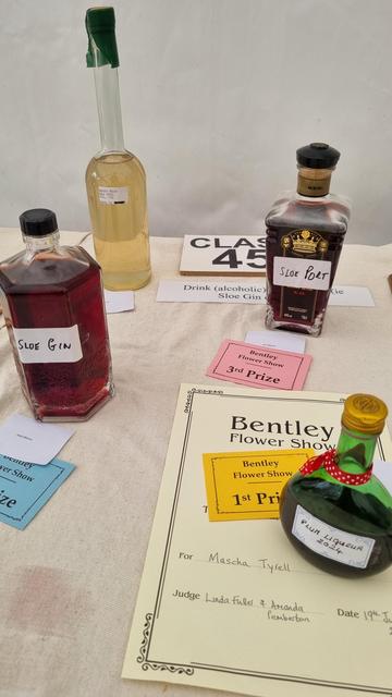 A table of home made alcoholic drinks, such as damson gin. They've been judged.