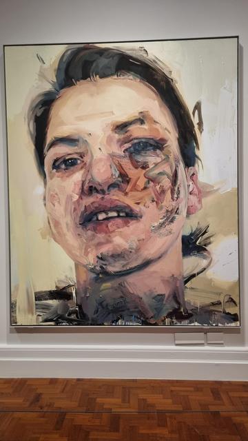 A face, portrayed in strong, rough brush strokes, looks out at you with a "Yeah, what of it?" kind of expression. The painting is a good 10ft tall, and the colours are not blended, but laid on thickly and in strangely messy lines, but the overall face is perfectly realistic and anatomically correct.