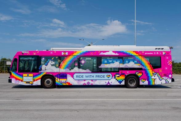 A very colourful bus featuring a rainbow on the side 