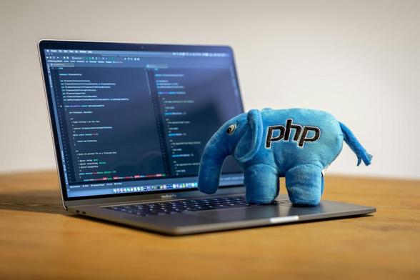 A laptop on a desk, with a PHP "Elephpant" toy on top of it.