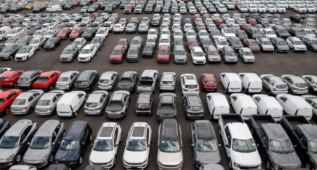 A car dealership lot has many cars lined up of various sizes and types