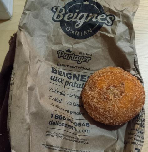 Un beigne aux patates recouvert de sucre et de cannelle posé sur le sac en papier brun des Délices d'antan.