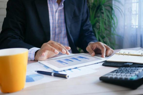 Photo of a businessman on a table using a tablet computer showing a graph on it. 