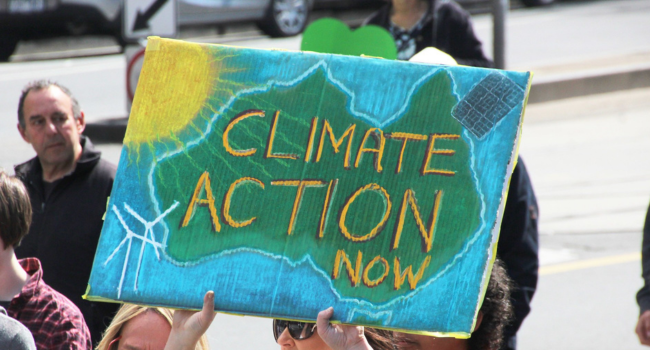 People holding up a banner reading CLIMATE ACTION NOW

against an outline of Australia, with symbols for the sun and wind farms
