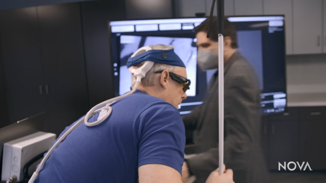 Screenshot from the video, showing blind brain implant recipient Brian Bussard and in the background Phil Troyk.